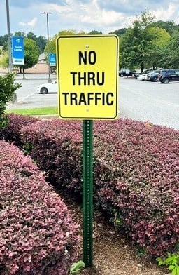 Yellow no thru traffic sign installed along neighborhood roadway