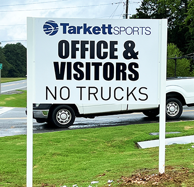 Custom post and panel directional sign for Tarkett Sports in Adairsville, Georgia, guiding office visitors while directing trucks to the proper entrance.